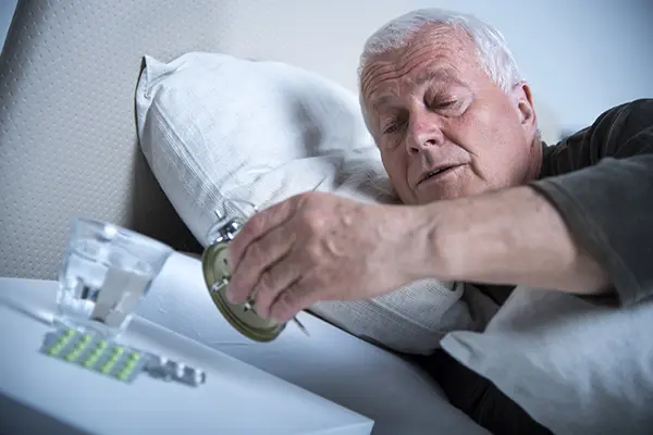 Senior man in bed looking at clock