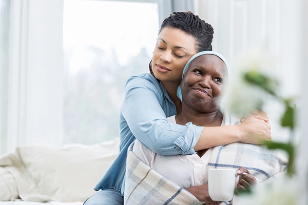 adult child embracing her ill senior mother