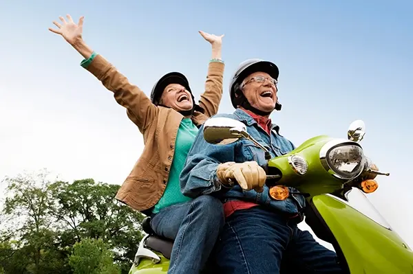 Senior couple having fun riding motor scooter.