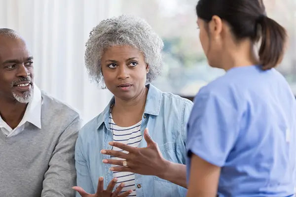 Senior woman and husband visit with doctor