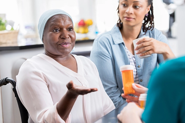 Senior female patient discusses concerns about her medication with an unrecognizable home healthcare nurse.