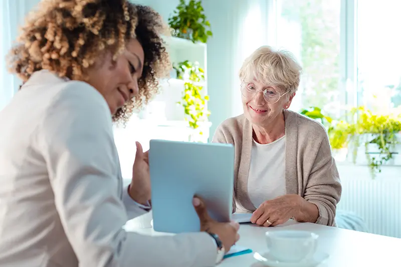 Smiling senior woman talking with advisor, sitting at the table.