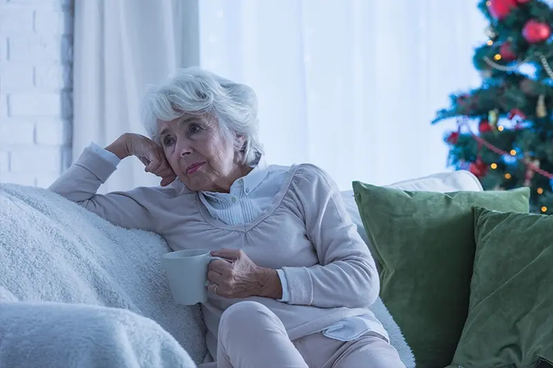 sad senior woman sitting on couch