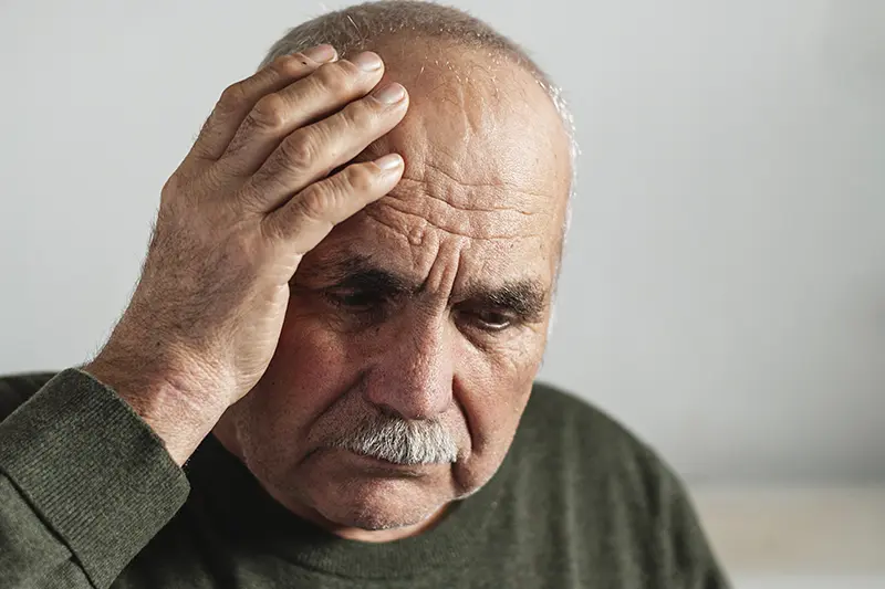 Elder man holding his head in discomfort