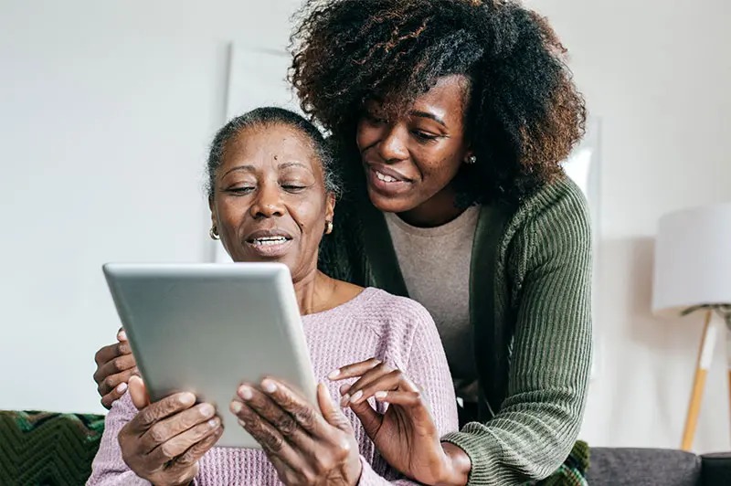 senior lady and adult daughter looking at tablet