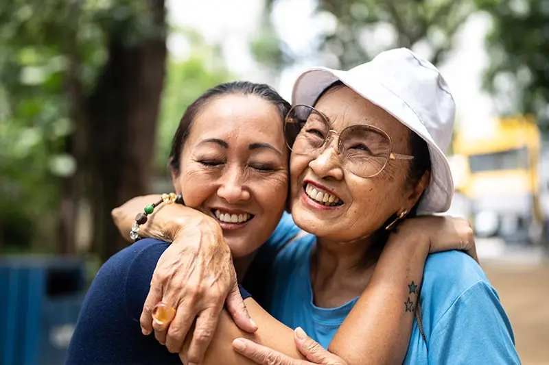 A daughter of a senior hugs the senior after learning tools for effective communication with seniors with dementia.